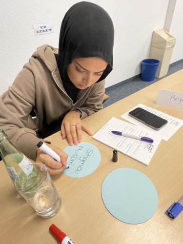Für das Brainstorming zur Gleichstellungspolitisch relevanten Themen und Herausforderungen für muslimische Frauen notiert Meryem Çerkeş das Stichwort "Stigma Muslima" auf einer Moderationskarte.